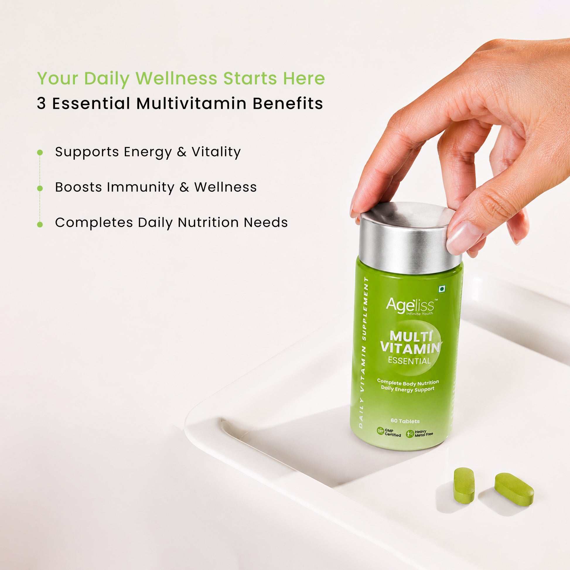 Hand placing Ageliss daily multivitamin supplement bottle on a clean white tray next to green tablets.